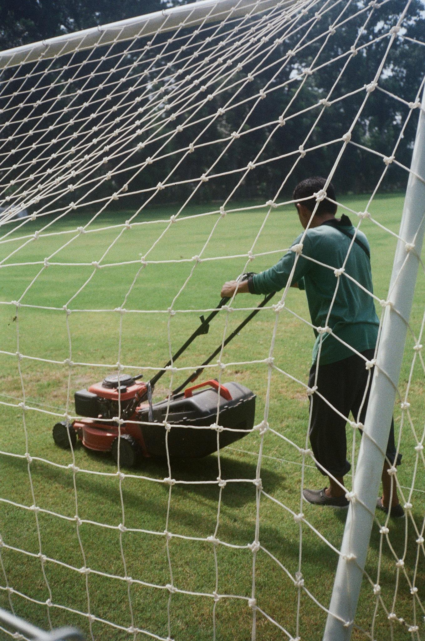 A gardener mowing the grass on a football field in Yogyakarta, Indonesia.